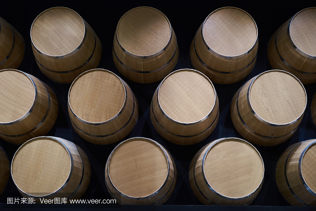 酒桶按顺序摆放在酒窖里,特写。堆叠葡萄酒桶