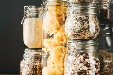 大米储存在木制桌子上的玻璃储存容器里,有各种各样的谷物产品和面食.