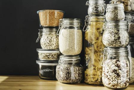 浪费粮食在木制桌子上的玻璃储存容器里,有各种各样的谷物产品和面食.