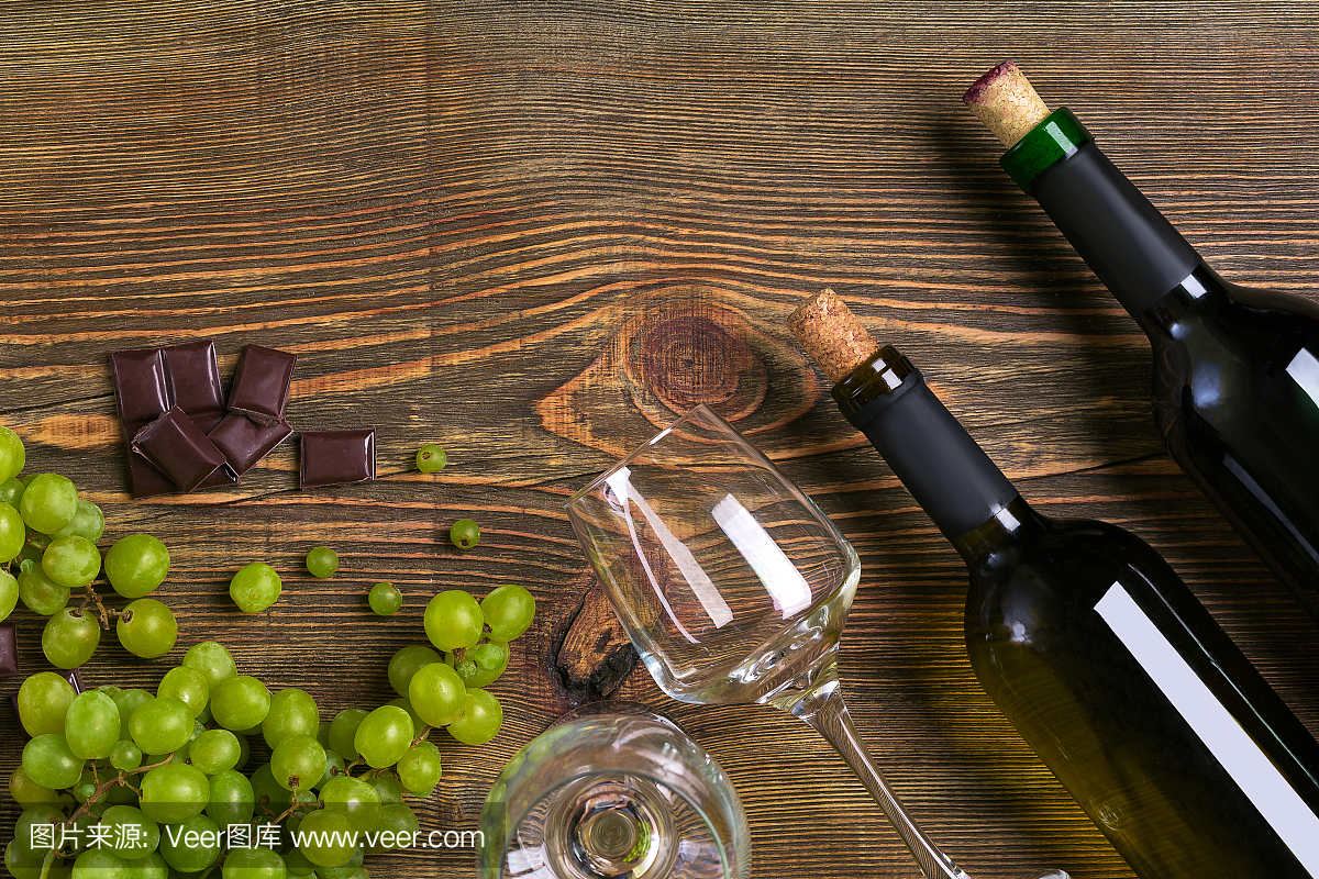 酒瓶和酒杯的葡萄酒,巧克力和成熟的葡萄在木制的背景